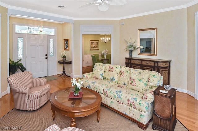 living room featuring light hardwood / wood-style flooring, crown molding, and ceiling fan with notable chandelier