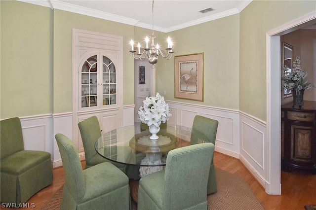 dining area featuring ornamental molding, light hardwood / wood-style floors, and a chandelier