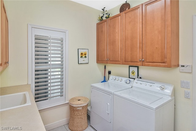 clothes washing area featuring sink, cabinets, light tile floors, and washing machine and clothes dryer