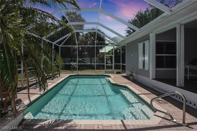 pool at dusk with a patio and a lanai