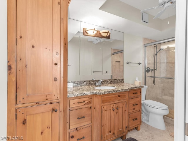 bathroom featuring a shower with door, tile floors, vanity, and toilet