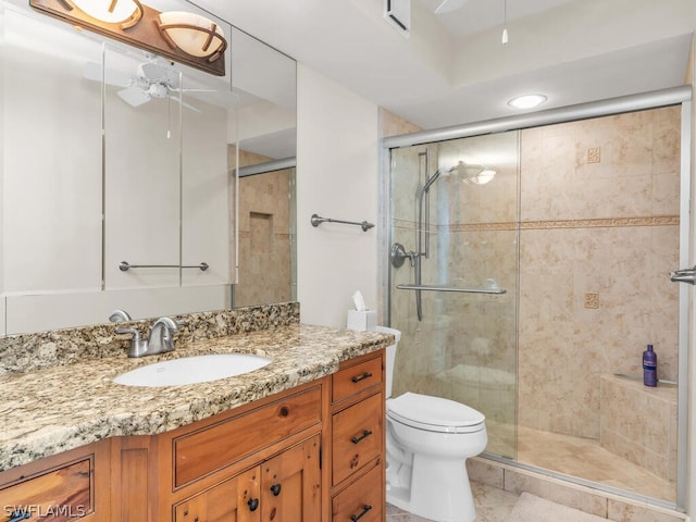 bathroom with a shower with door, ceiling fan, toilet, vanity, and tile floors