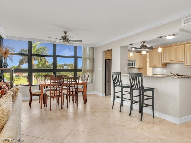 dining room with ceiling fan, crown molding, light tile floors, and expansive windows