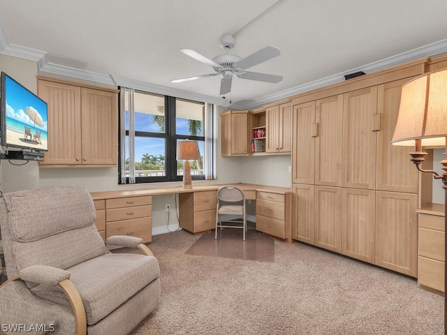 office space with light carpet, ornamental molding, ceiling fan, and built in desk