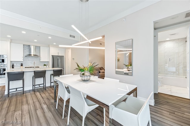 dining space featuring hardwood / wood-style floors, sink, and crown molding