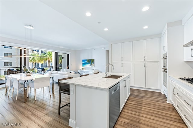 kitchen featuring a kitchen island with sink, white cabinets, sink, appliances with stainless steel finishes, and light hardwood / wood-style floors