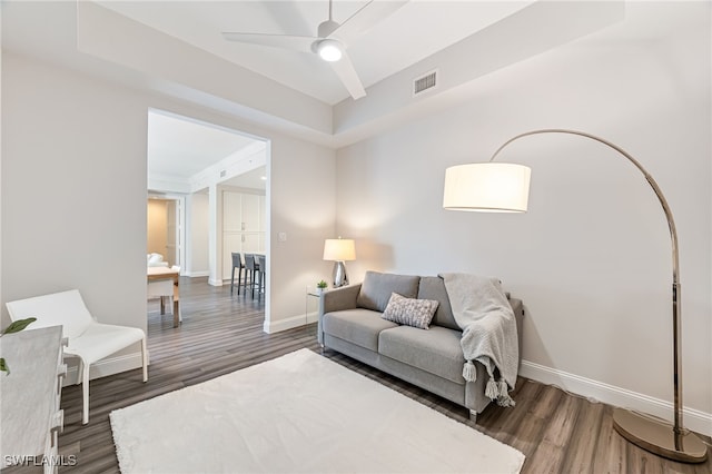 living room with ceiling fan and dark wood-type flooring