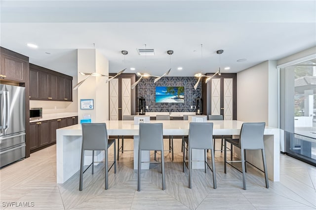 kitchen featuring a center island, a kitchen breakfast bar, pendant lighting, dark brown cabinets, and appliances with stainless steel finishes