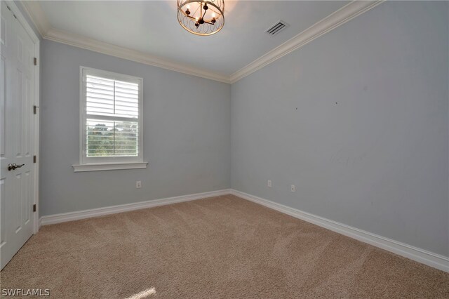 spare room featuring an inviting chandelier, crown molding, and light colored carpet