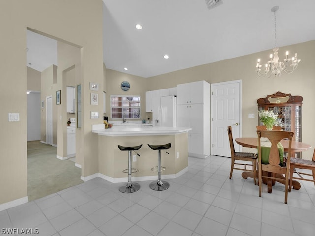 kitchen with white cabinets, white refrigerator, light tile floors, and a kitchen bar