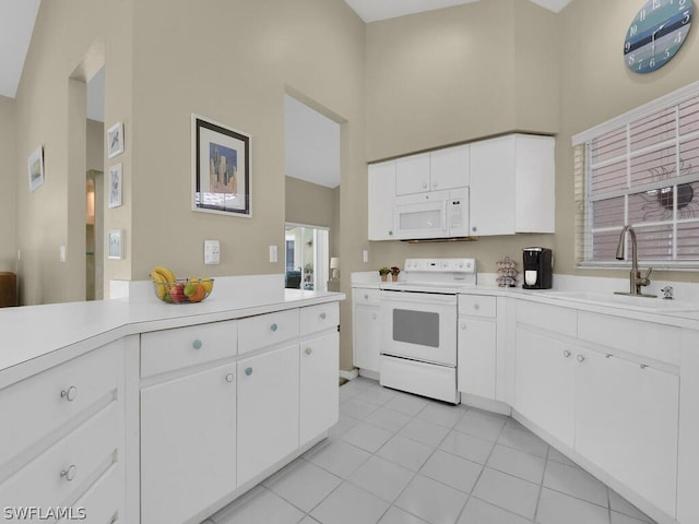 kitchen with white cabinets, white appliances, a towering ceiling, light tile floors, and sink