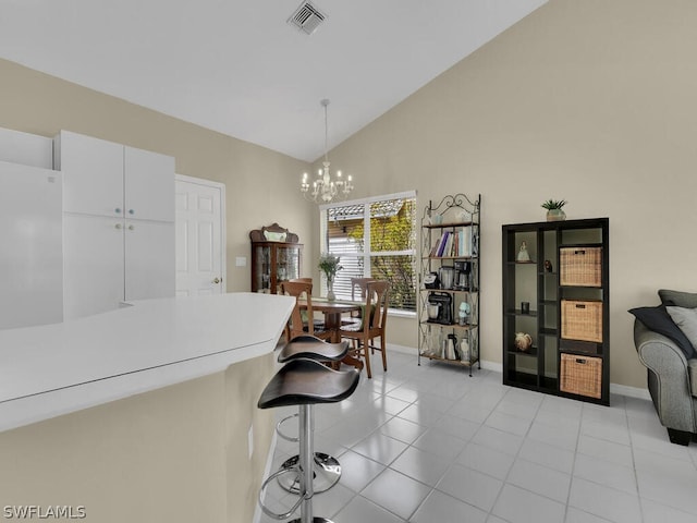 kitchen with decorative light fixtures, white cabinets, vaulted ceiling, light tile floors, and a notable chandelier