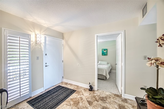 entryway with a textured ceiling and light tile floors