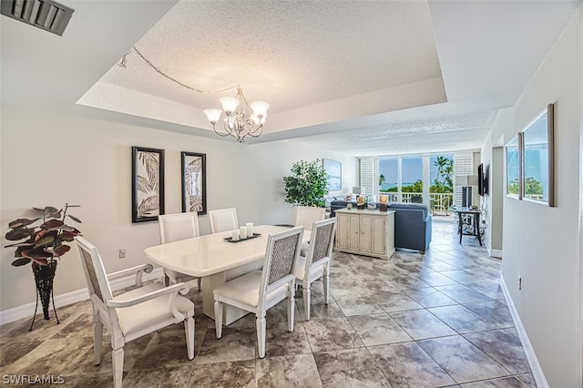 dining area featuring a textured ceiling, light tile flooring, a tray ceiling, and an inviting chandelier