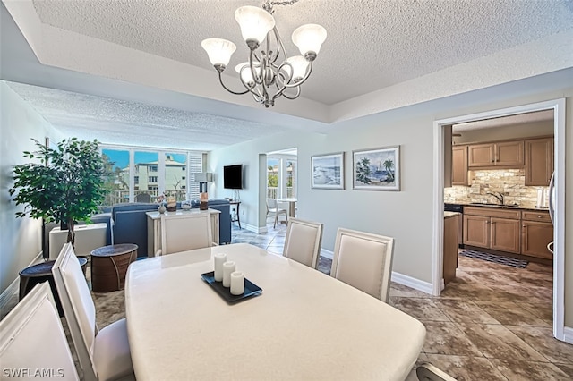 tiled dining area with sink, a textured ceiling, and a notable chandelier