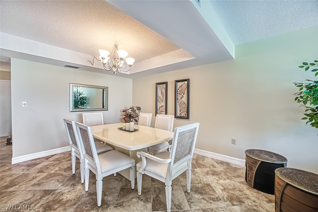 tiled dining space featuring a textured ceiling, a raised ceiling, and a notable chandelier