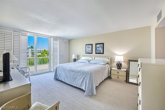 bedroom with light colored carpet, a textured ceiling, and access to exterior