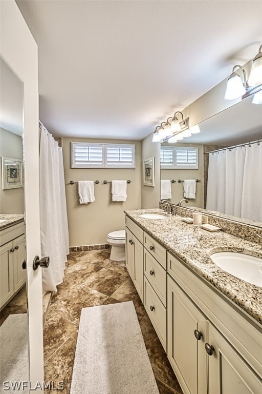 bathroom featuring tile floors, toilet, and double vanity