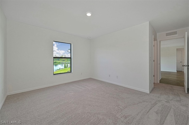 unfurnished room with a water view and light carpet