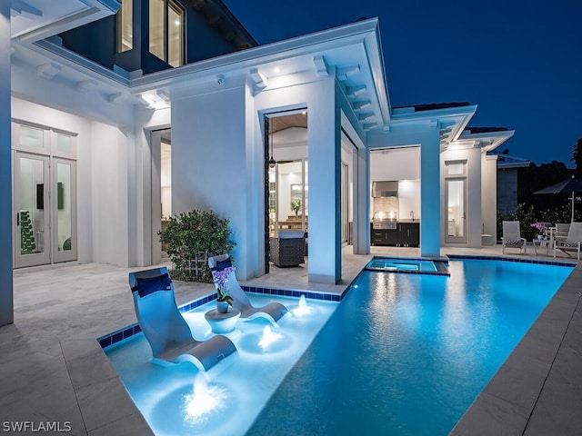 pool at night featuring a patio area and french doors