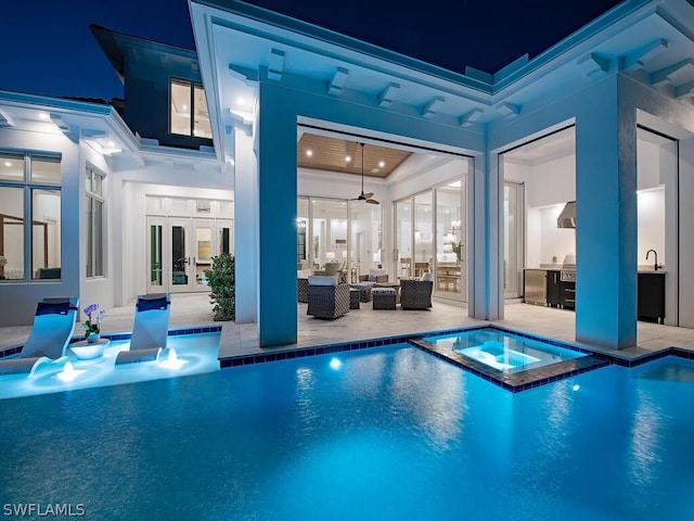 pool at night with outdoor lounge area, french doors, ceiling fan, an in ground hot tub, and a patio area