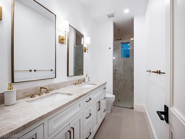 bathroom featuring tile patterned flooring, toilet, a tile shower, and vanity