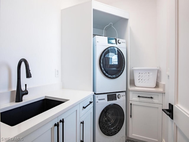 clothes washing area featuring cabinets, stacked washer and dryer, and sink