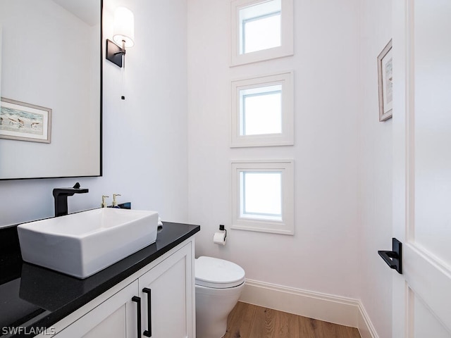 bathroom with a healthy amount of sunlight, vanity, wood-type flooring, and toilet