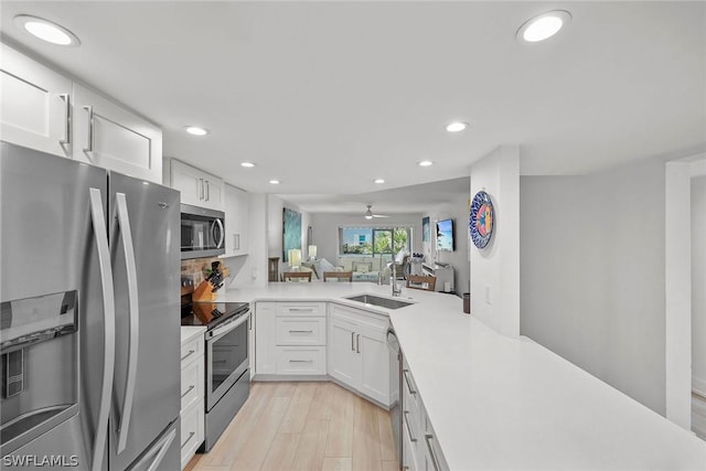 kitchen featuring appliances with stainless steel finishes, kitchen peninsula, sink, and white cabinets