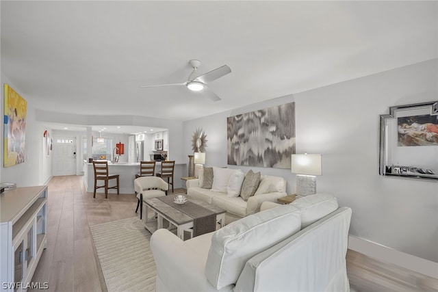 living room with ceiling fan and light wood-type flooring