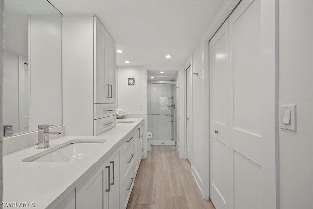 bathroom featuring vanity, hardwood / wood-style floors, a shower with door, and toilet