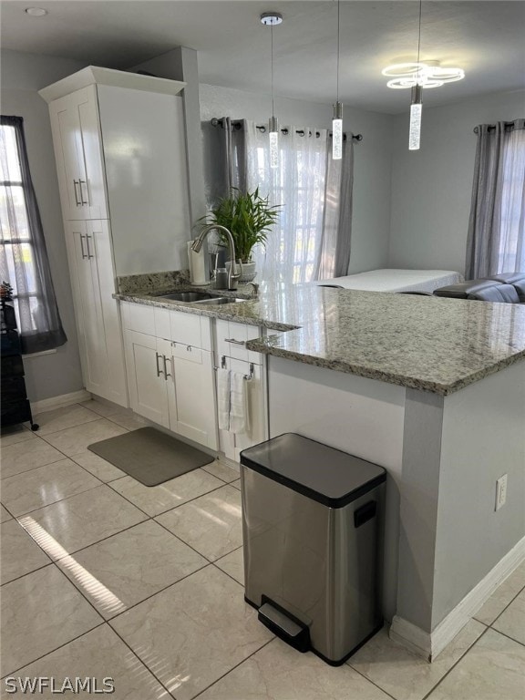 kitchen with white cabinets, sink, light stone countertops, and light tile flooring