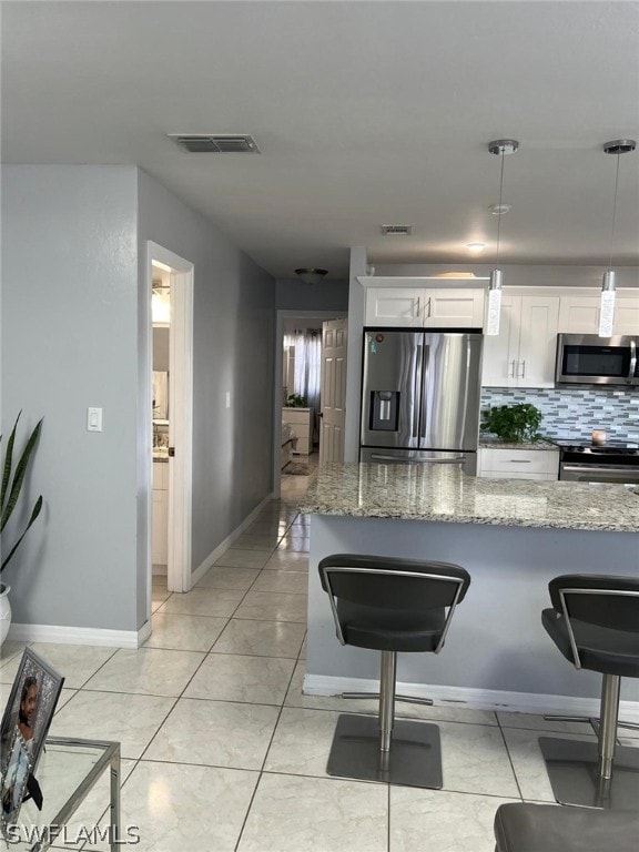 kitchen featuring appliances with stainless steel finishes, light stone counters, backsplash, and white cabinetry