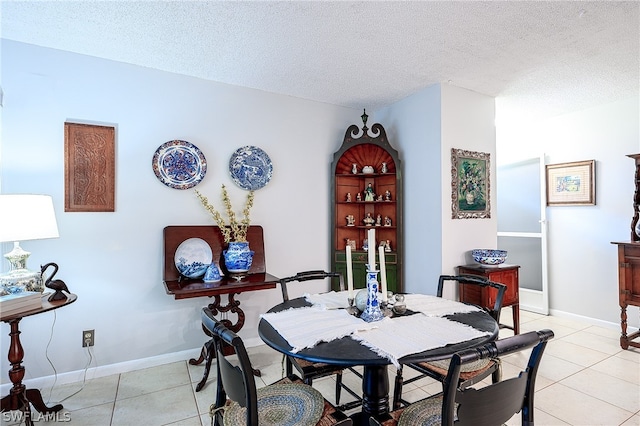 dining room with light tile patterned flooring, a textured ceiling, and baseboards