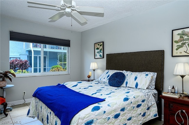 bedroom with a textured ceiling, ceiling fan, light tile patterned floors, and baseboards