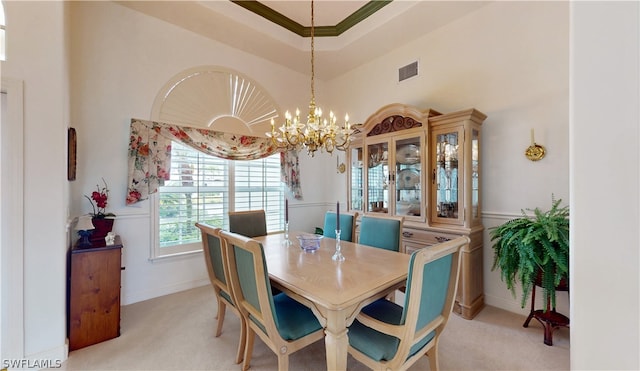 dining space with a chandelier, light colored carpet, a raised ceiling, and crown molding