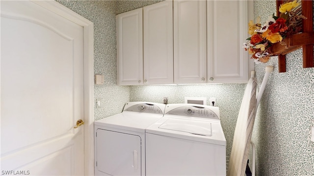 clothes washing area featuring cabinets and washing machine and clothes dryer