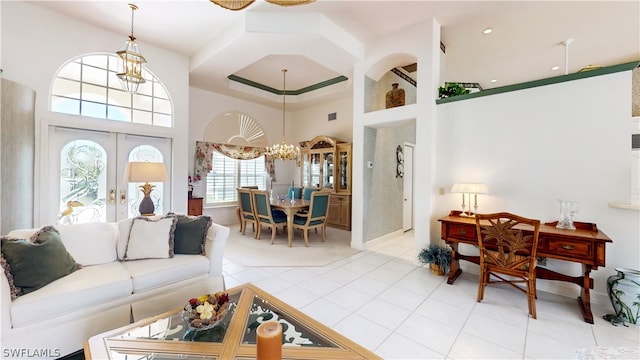 tiled living room with a chandelier, french doors, and a high ceiling