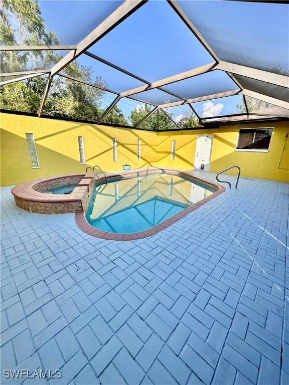 view of pool with an in ground hot tub, a lanai, and a patio area