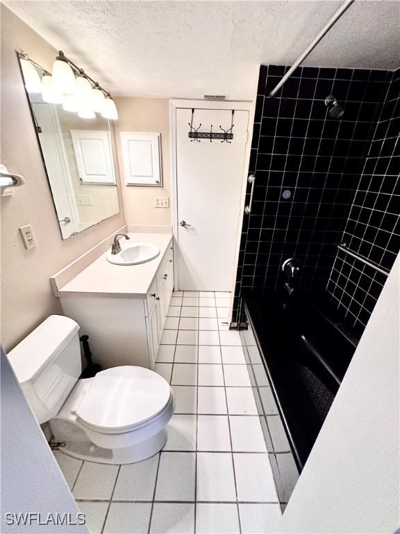 full bathroom with vanity, a textured ceiling, tile patterned floors, toilet, and tiled shower / bath