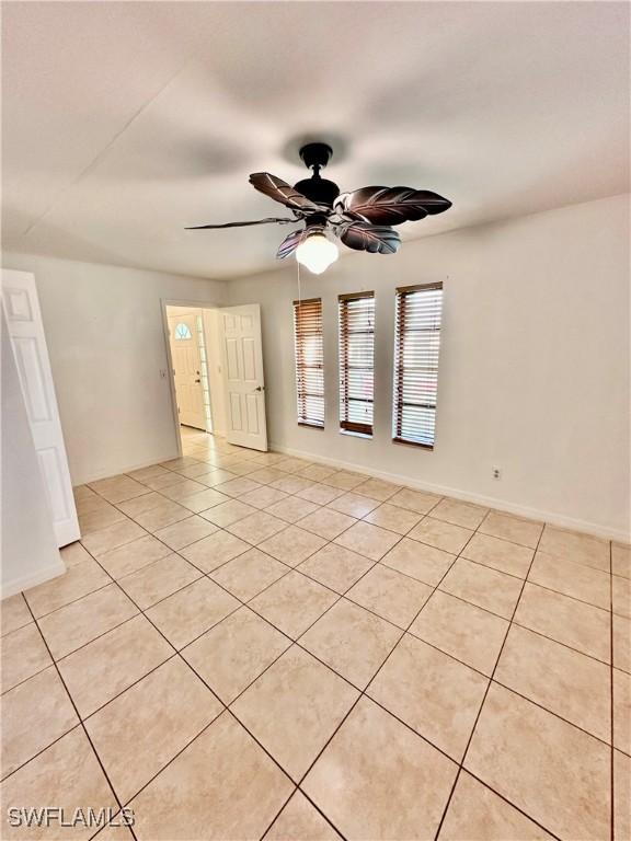 tiled empty room featuring ceiling fan