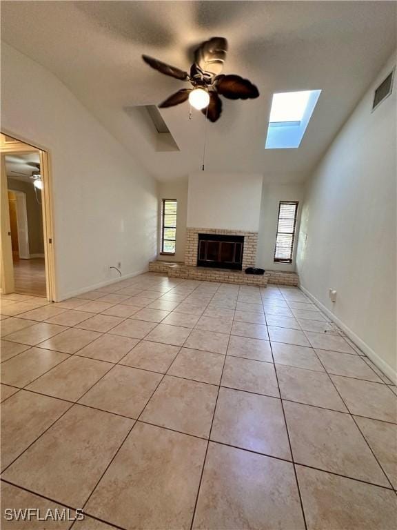 unfurnished living room with a fireplace, lofted ceiling with skylight, and light tile patterned floors