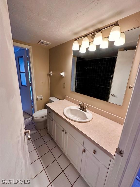 bathroom with vanity, tile patterned floors, a textured ceiling, and toilet