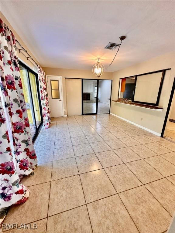 tiled spare room with an inviting chandelier