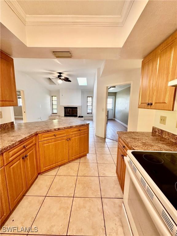 kitchen with light tile patterned floors, white electric range oven, ceiling fan, and a tray ceiling