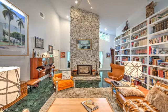 living area featuring visible vents, a stone fireplace, and a towering ceiling