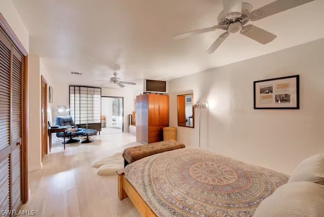 bedroom featuring a ceiling fan, a closet, visible vents, and light wood-style flooring