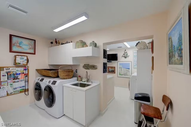 clothes washing area with cabinet space, washing machine and dryer, visible vents, and a sink