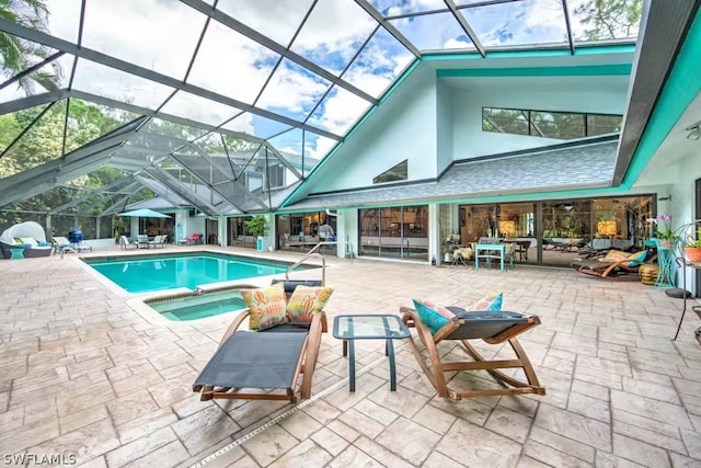 outdoor pool with glass enclosure, a patio, and an in ground hot tub