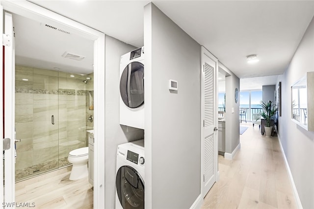 laundry room featuring light hardwood / wood-style flooring and stacked washing maching and dryer